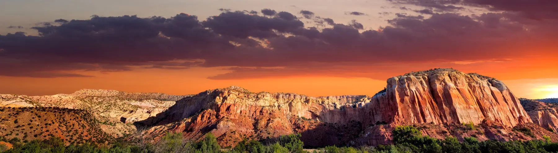 Scenic view of Ghost Ranch, showing red rock formations and sunset sky, the location of the EMDR and Mindfulness retreat for licensed clinicians.