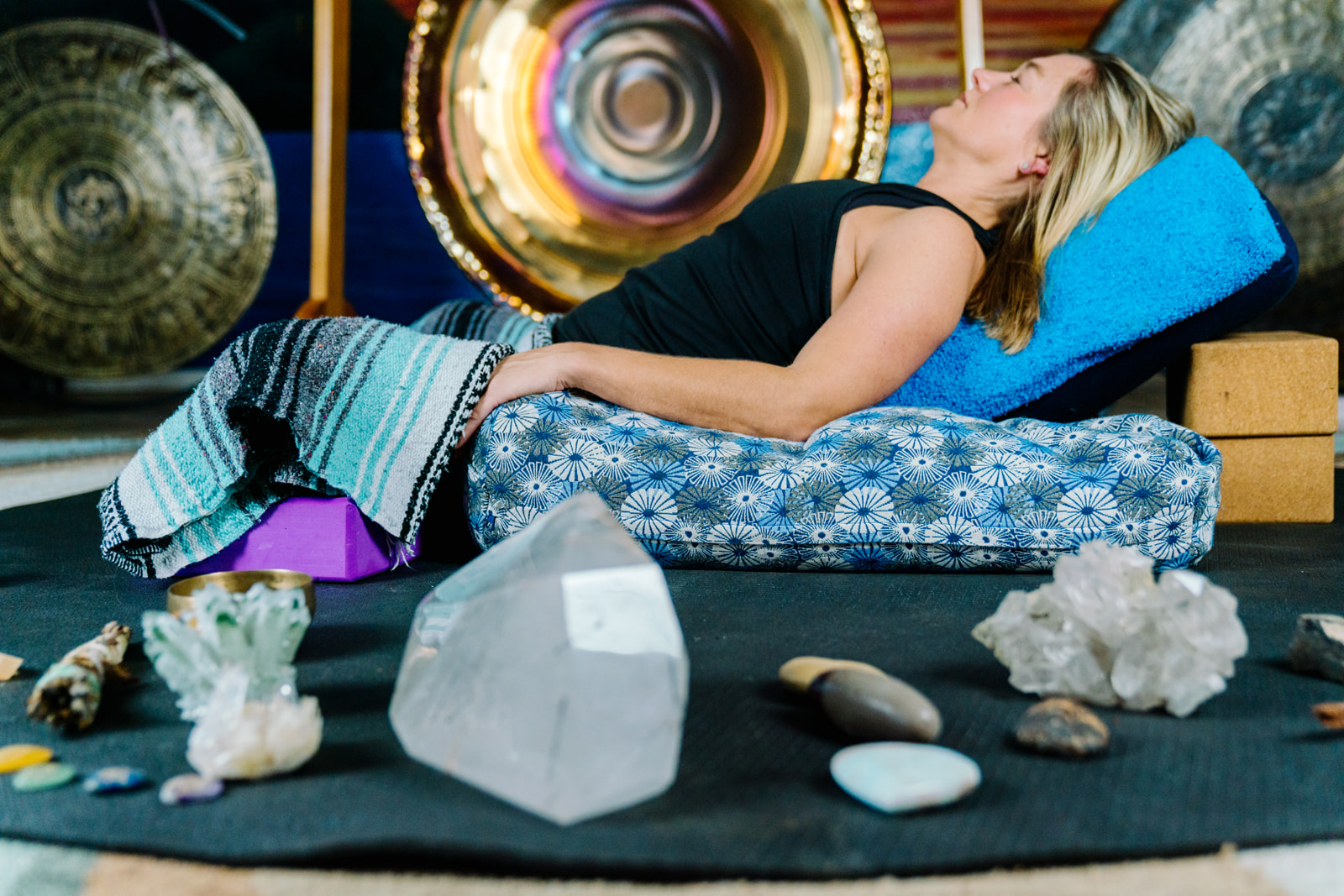 Lady lying in yoga pose relaxed with crystals