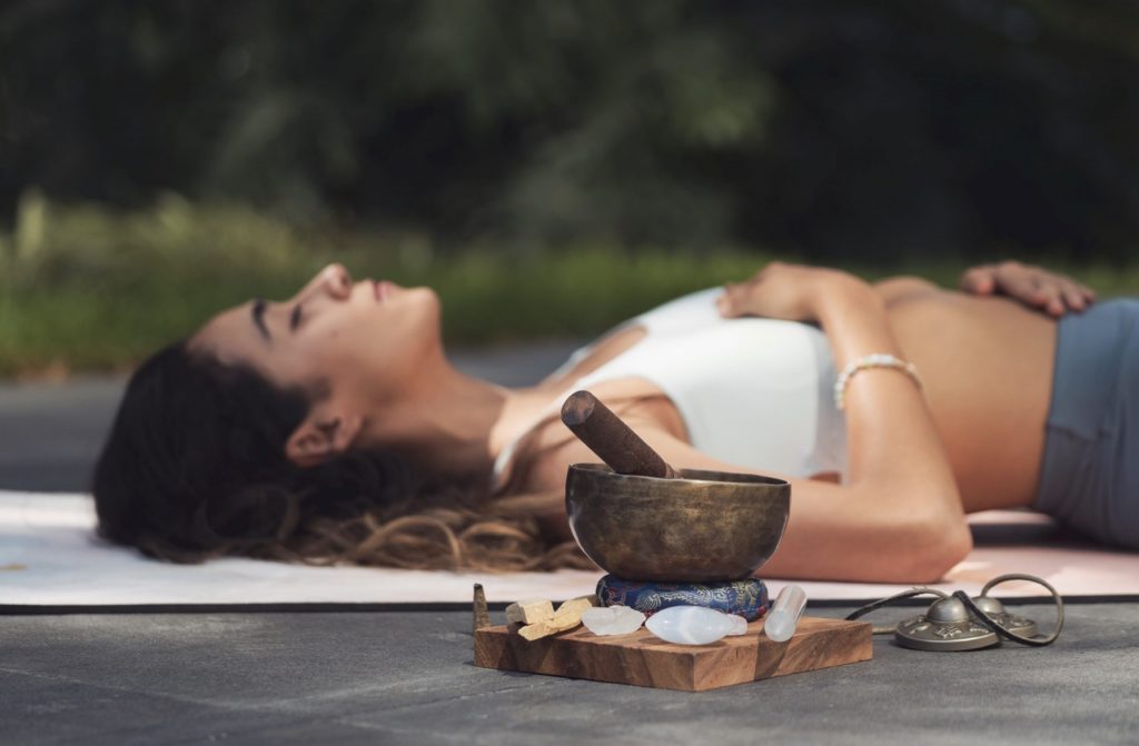 woman lying on floor meditating in yoga with sound bath